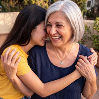 Thumbnail for Grandmother hugging her granddaughter, wearing the gold secret heart photo necklace | SKU: TPH-CHTN-GOLD-SMALL