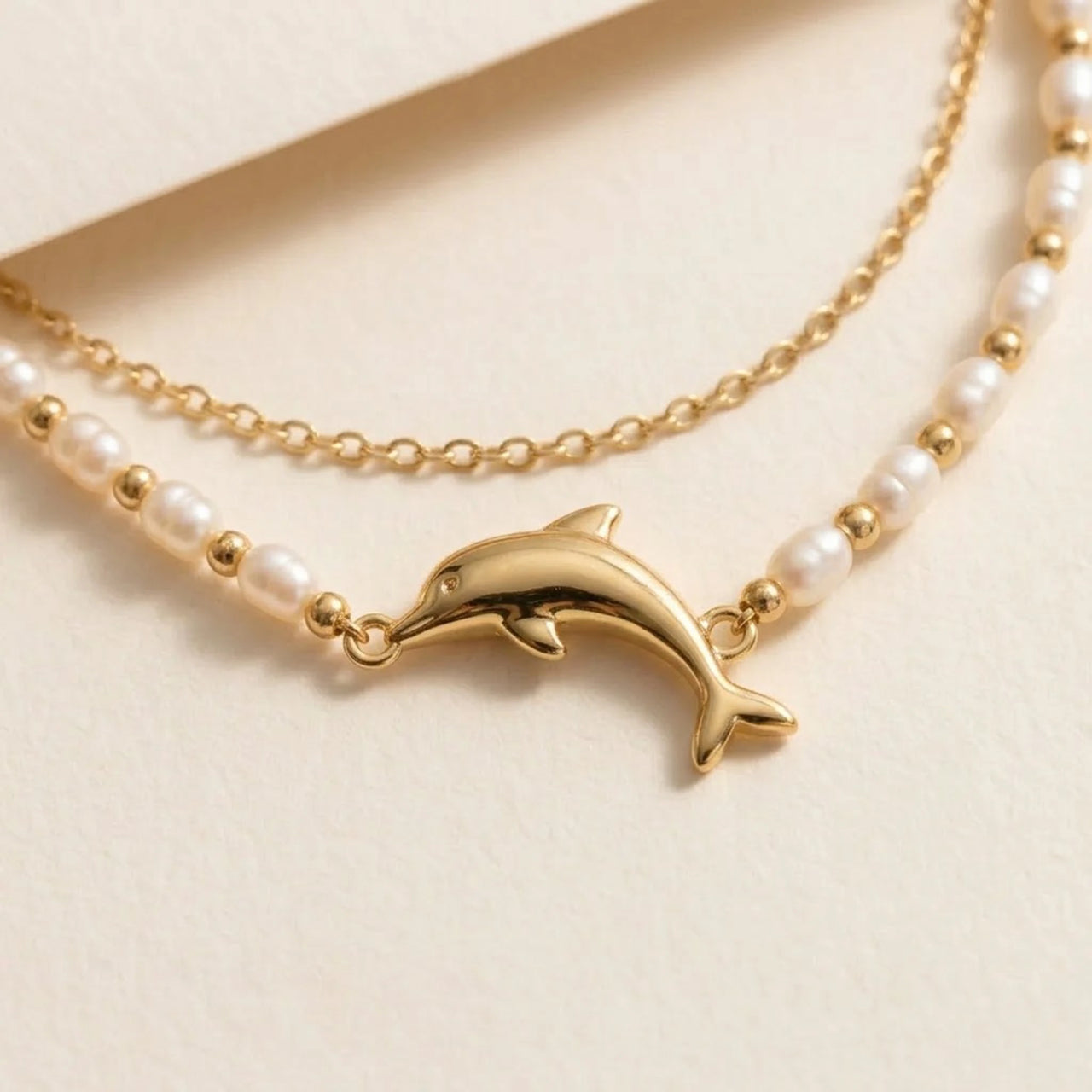 Close-up of the Pearl Dolphin Anklet Set: gold dolphin charm set between freshwater pearls, with a fine gold cable chain, by Brother & Sisters.