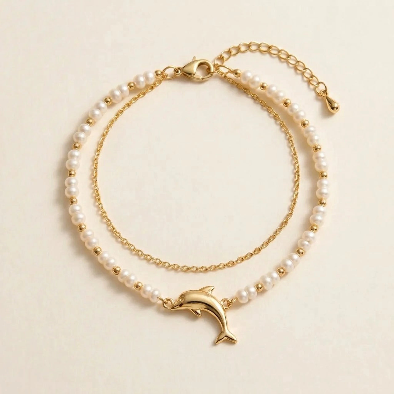 Pearl Dolphin Anklet Set laid flat, showing the pearl strand, the fine gold cable chain and the gold dolphin charm, by Brother & Sisters.