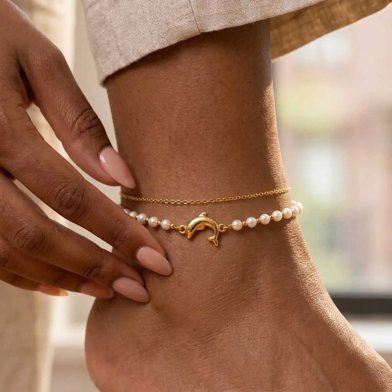 Pearl Dolphin Anklet Set on the ankle, freshwater pearls and a gold dolphin charm on a delicate double strand, by Brother & Sisters.