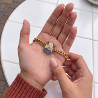 Thumbnail for Thumb warming the gold cushion bracelet plate: the hidden photo appears under the thumb while the rest stays black | SKU: TPH-CUSB-GOLD